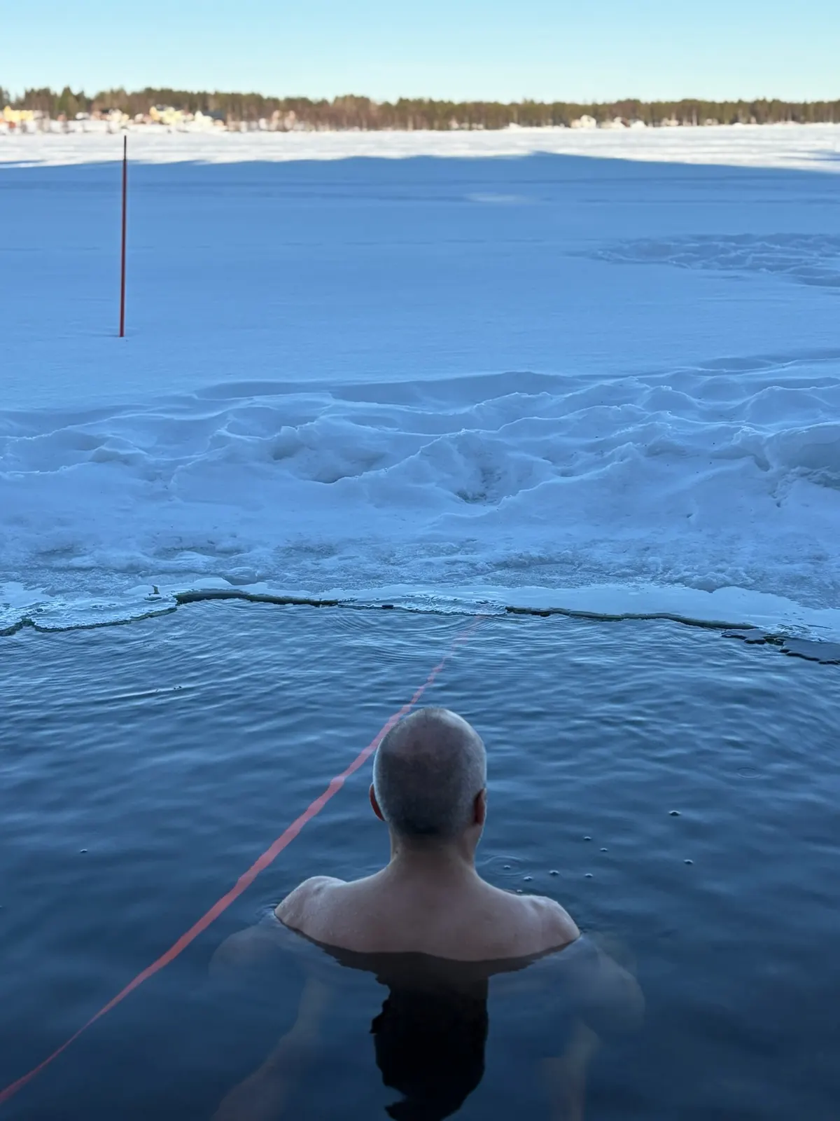 Robert Mittl beim Eisbaden in einem Eisloch in Lappland, Blick über den zugefrorenen See