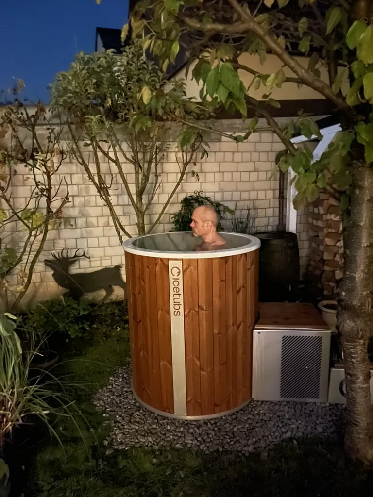 Robert Mittl sitzt bei der Einweihung in seiner Icetubs-Eistonne im Garten